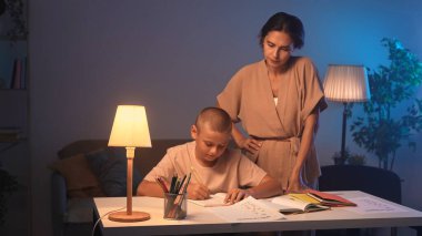 Bir öğrenci bir odada bir masada oturur ve ev ödevini yapar. Bir genç akşam karanlık bir odada ders çalışıyor ve annesi onun ev ödevini yapmasına yardım ediyor. Eğitim ve öğrenim kavramı.