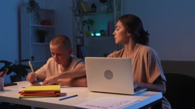 Bir öğrenci bir odada bir masada oturur ve ev ödevini yapar. Bir genç akşam karanlık bir odada ders çalışıyor ve annesi onun ev ödevini yapmasına yardım ediyor. Eğitim ve öğrenim kavramı.