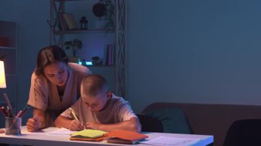 Bir öğrenci bir odada bir masada oturur ve ev ödevini yapar. Bir genç akşam karanlık bir odada ders çalışıyor ve annesi onun ev ödevini yapmasına yardım ediyor. Eğitim ve öğrenim kavramı.