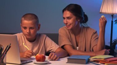 Bir öğrenci bir odada bir masada oturur ve ev ödevini yapar. Bir genç akşam karanlık bir odada ders çalışıyor ve annesi onun ev ödevini yapmasına yardım ediyor. Eğitim ve öğrenim kavramı.