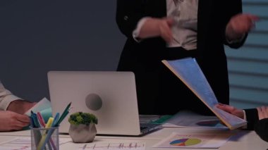 Proje lideri ve ekip üyeleri buluşuyor. Kadın yöneticiler, çalışma odasındaki çalışma arkadaşlarıyla toplantıyı yönetiyor. Projeyi olumlu bir şekilde kapatıyorlar. Masanın ve insanların yakın plan fotoğraflarını çekiyorlar..