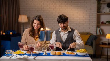 Aile tatil için hazırlanıyor. Geleneksel Hanuka kutlamalarına hazırlanan Yahudi çift, masada oturan erkek ve kadın, akşam yemeğinin ve sohbetin keyfini çıkarıyorlar, pozitif ifade.