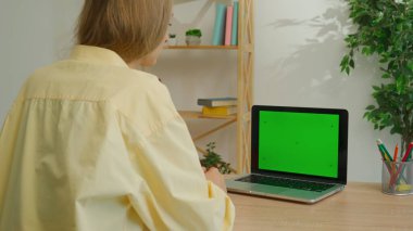 Çevrimiçi kursa katılan kişi. Kadın üniversite öğrencisi evde ders çalışıyor, internetten krom anahtar yeşil ekran çalışma alanı modeliyle ders izliyor. Modern online eğitim.
