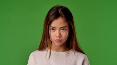 Çocuk duyguları konsepti. Üzgün suratlı Asyalı bir çocuk kameraya bakıyor, negatif yüz ifadesi, krom anahtar yeşil ekranda izole edilmiş, arka plan modeli..
