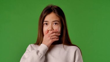 Çocuk duyguları konsepti. Şok olmuş suratlı Asyalı bir çocuk kameraya bakıyor, yüzünü elleriyle kapatıyor, korkmuş bir ifade, krom anahtar yeşil ekran arka plan modelinde izole edilmiş..