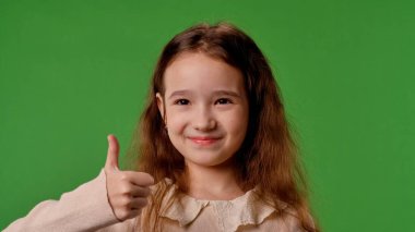 Çocuk duyguları konsepti. Küçük kız kameraya bakar ve el işaretini gösterir, olumlu ifade, krom anahtar yeşil ekran arka plan modelinde izole edilmiş..