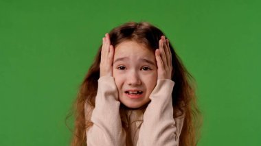 Çocuk duyguları konsepti. Şok olmuş yüzü olan bir kız kameraya bakar, yüzünü elleriyle kapatır, korkmuş bir ifade, krom anahtar yeşil ekranda izole edilmiş, arka plan modeli..