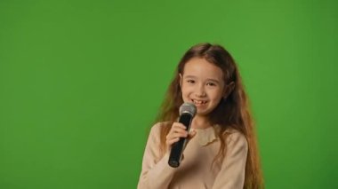 Çocuk duyguları konsepti. Karaoke mikrofonunda şarkı söyleyen küçük kız çocuğu, pozitif ifade, krom anahtar yeşil ekranda izole edilmiş arka plan modeli..