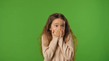 Çocuk duyguları konsepti. Şok olmuş yüzü olan bir kız kameraya bakar, yüzünü elleriyle kapatır, korkmuş bir ifade, krom anahtar yeşil ekranda izole edilmiş, arka plan modeli..