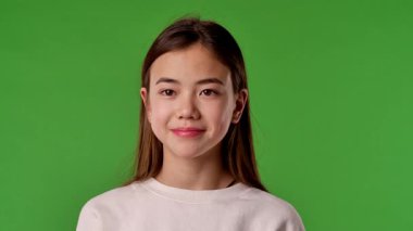 Çocuk duyguları konsepti. Asyalı kız çocuğu kameraya bakıyor ve gülümsüyor, pozitif ifade, krom anahtar yeşil ekranda izole edilmiş arka plan modeli..