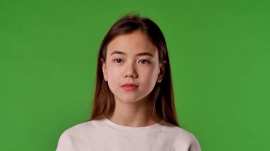 Çocuk duyguları konsepti. Asyalı kız çocuğu etrafına bakıyor ve kameraya el sallıyor, pozitif ifade, krom anahtar yeşil ekranda izole edilmiş arka plan modeli..