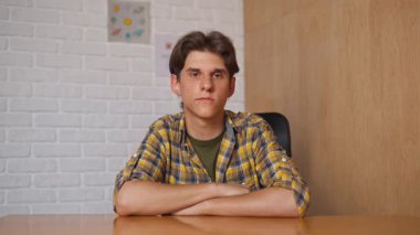 Çevrimiçi kursa katılan kişi. Üniversitede okuyan erkek öğrenci, masa başında oturuyor, bilgisayar dersini dinliyor, öğretmenini selamlıyor, el sallıyor. Modern online eğitim.