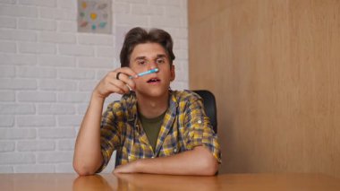 Çevrimiçi kursa katılan kişi. Üniversitede okuyan erkek öğrenci, masa başında oturuyor, internette ders dinliyor, soruları cevaplıyor. Modern online eğitim.