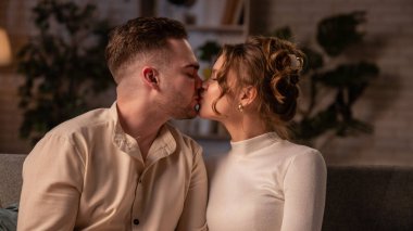 Sevgililer Günü 'nde evde birlikte olan sevimli bir çift. Sevgililer Günü 'nü evde kutlayan mutlu bir çift. Kanepede oturan ve öpüşen bir kadın ve bir erkek..