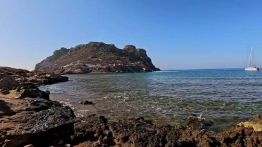 İspanya kıyılarının nefes kesen manzarası, engebeli uçurumları, kuru tepeleri ve parçalı bulutlu gökyüzünün altındaki sakin denizi. Temiz turkuaz suyu olan tenha bir körfez bozulmamış güzelliği tamamlıyor.