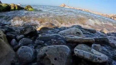 İspanya 'da kayalık bir kıyı şeridine yakın, berrak su kayaların üzerinden Akdeniz' e doğru yavaşça akıyor. Karanlık, ıslak kayalar yumuşak gökyüzü ile tezat oluşturarak sakin bir kıyı manzarası yaratıyor..