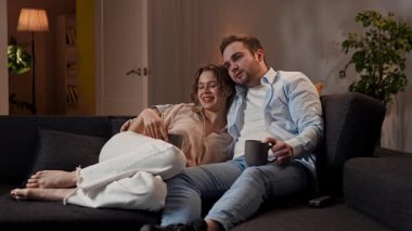 Mutlu çift birlikte vakit geçiriyor. Hoş bir çift evdeki kanepede dinleniyor, kadın ve erkek televizyon seyrediyor, birbirlerine sarılıyor, çay içiyor, mutlu bir ifade sergiliyorlar. Yavaş çekim.