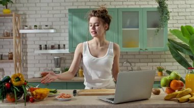 Sağlıklı beslenme konsepti. Mutfaktaki masada genç bir kadın sağlıklı öğle yemeği için börek hazırlıyor. Yemek blogcusu kadın kameraya konuşuyor. Atıştırmalık malzemeler gösteriyor. Yavaş çekim.