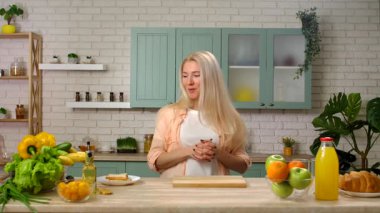 Aşçılık programının kaydı. Kadın sunucu mutfakta kahvaltı hazırlıyor, konuşuyor ve gülümsüyor profesyonel stüdyodaki bir televizyon programının video kaydı. Yavaş çekim.