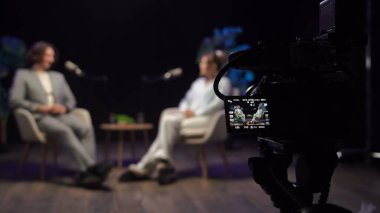 Bir podcast stüdyosunda, hikaye anlatma deneyimlerini belgelemek için mikrofon ve kameralardan yararlanarak dinleyicilere ilham veren bir medya oluşturan iki etkili kişi ilgi çekici bir tartışmaya girişiyor. Sahne arkasında