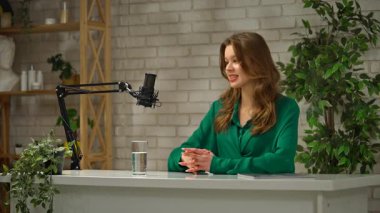 Genç bir bayan sunucu canlı bir stüdyo ortamında röportaj veya uzman videosu çeker. Podcast 'ini profesyonel bir mikrofon ve stüdyo ile kaydederek en son konulardaki düşüncelerini paylaşıyor.