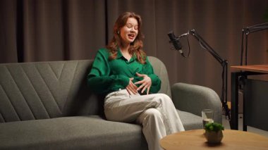 Genç bir bayan sunucu canlı bir stüdyo ortamında röportaj veya uzman videosu çeker. Podcast 'ini profesyonel bir mikrofon ve stüdyo ile kaydederek en son konulardaki düşüncelerini paylaşıyor.