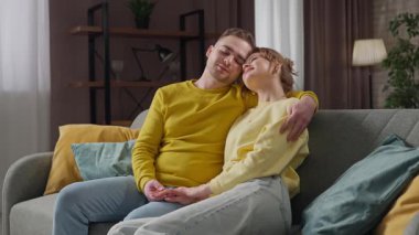 Sevgililer gününde harika bir çift. Sevgililer Günü 'nü evde kutlayan mutlu çift, kanepede oturan erkek ve kadın, sarılıp sohbet ediyorlar, mutlu bir ifade. Yavaş çekim.
