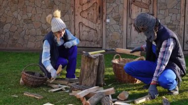 Bir çift doğranmış kütük topluyor. Soğuk kış aylarında sobanın ısınması için odun hazırlamak üzere bir takım olarak çalışırlar. Sıcak giyimli bir aile güneşli bir kış gününde birlikte çalışıyor..