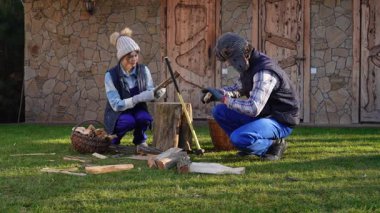 Bir çift doğranmış kütük topluyor. Soğuk kış aylarında sobanın ısınması için odun hazırlamak üzere bir takım olarak çalışırlar. Sıcak giyimli bir aile güneşli bir kış gününde birlikte çalışıyor..