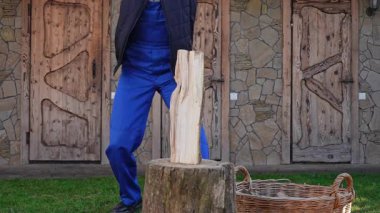 Güneşli bir kış gününde mavi tulumlu bir adam odun kesiyor. Kırsal atmosfer. Kış için odun kesiyorum..