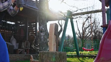 Güneşli bir kış gününde mavi tulumlu bir adam odun kesiyor. Kırsal atmosfer. Kış için odun kesiyorum..