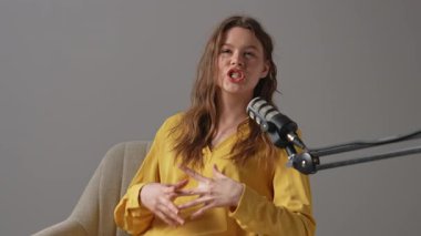 Stüdyoda rahat bir kadın, uzman videosu çekerken tutkuyla fikirleri tartışıyor. Sarı bluzlu blogcu kadın markalaşma ve iş geliştirme stratejisinden bahsediyor.