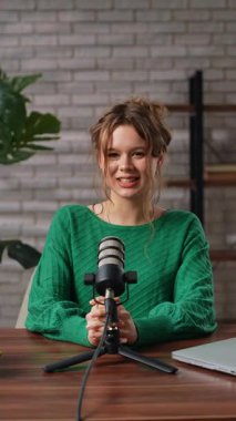 Stüdyoda rahat bir kadın, uzman videosu çekerken tutkuyla fikirleri tartışıyor. Yeşil kazaklı blogcu kadın markalaşma ve iş geliştirme stratejisinden bahsediyor. Dikey video.