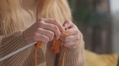 Turuncu iplikle örgü ören bir kadının elleri. Evinde oturmuş el işi yapan bir kadın var. Yavaş çekim