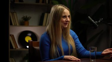 Podcastlar için modern bir stüdyo stüdyosunda, bir kadın ya röportaj yapar ya da başarılarını paylaşır. Bir mikrofon, öykü ortaya çıktığında her kelimeyi yakalar. Video günlüğü, içerik kaydı.