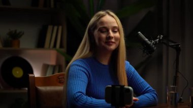Podcastlar için modern bir stüdyo stüdyosunda, bir kadın ya röportaj yapar ya da başarılarını paylaşır. Bir mikrofon, öykü ortaya çıktığında her kelimeyi yakalar. Video günlüğü, içerik kaydı.