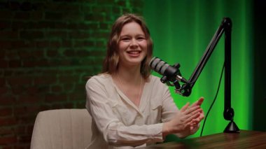 İki uzman selamlaşmada el sıkışıyor. Bir erkek ve bir kadın deneyimlerini şık bir podcast stüdyosunda mikrofonlu yeşil ışıklarla paylaşıyorlar..