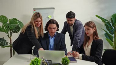 Çeşitli iş adamları modern bir ofiste stratejileri tartışıyor ve başarının tadını çıkarıyor. Bir dizüstü bilgisayarda takım olarak çalışıyorlar ve arka planda bir iş fikri tahtası var..