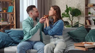 Hafta sonları birlikte birkaç boş zaman geçiririz. Çift evdeki kanepede dinleniyor, kadın ve erkek televizyon izliyor ve birbirlerini pizza ile besliyorlar, gülümsüyor ve atıştırmalıkların tadını çıkarıyorlar. Yavaş çekim.