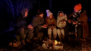 Bir grup genç arkadaş gece bir kamp ateşinin etrafında toplanmış, bir tanesi gitar çalarken müziğin keyfini çıkarıyorlardı. Sıcak kış kıyafetleri giymişler, birlikte gülüyorlar ve şarkı söylüyorlar..