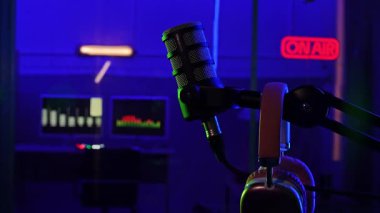 Renk değiştiren neon ışıklı profesyonel bir podcast mikrofon. Ses mühendisi ve ışık odimetreleri bulanık bir arkaplan karşısında gösterilir ve atmosferi oluşturur.