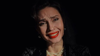 Stüdyoda profesyonel model. Siyah arka planda izole edilmiş, eski moda saç stili ve makyajlı kadın oyuncu, komik bir şekilde gülümseyen kadın yüzü..