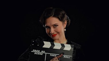 Stüdyoda profesyonel model. Siyah arka planda izole edilmiş kameraya poz veren eski moda saç stili ve makyajlı kadın oyuncu, gülümseyen ve poz veren kadın..