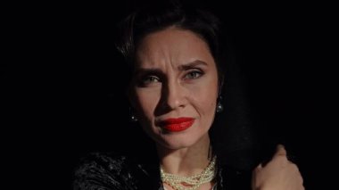 Stüdyoda profesyonel model. Siyah arka planda izole edilmiş saç stili ve makyajlı, geçmişe dönük kadın oyuncu kameraya bakıyor ve üzüntüden deli gibi bağırıyor. Yavaş çekim.