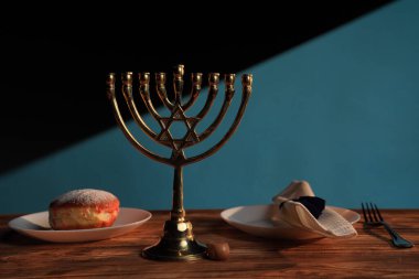 Geleneksel bir çörek ve peçeteyle çevrili bir Hanuka menorası, Yahudi kutlamalarını simgeliyor..