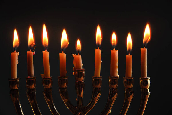 Менора с девятью зажженными свечами символизирует еврейский праздник Хануки, отмечаемый в течение восьми ночей.