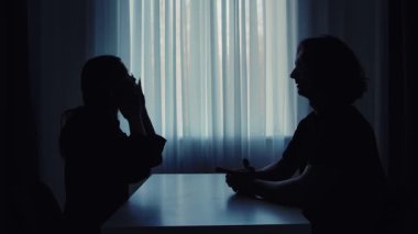 Siluetli bir çift, arka plandaki ışığa karşı hararetli bir tartışmaya girerek çatışma dinamiklerini gösteriyor..