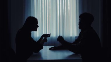 Siluetli bir çift, arka plandaki ışığa karşı hararetli bir tartışmaya girerek çatışma dinamiklerini gösteriyor..