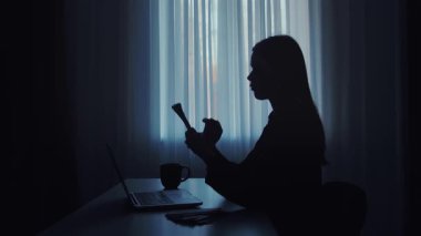 Loş bir odada para sayan bir kişinin silüeti. Yakınlardaki masanın üzerine bir bardak su konur..