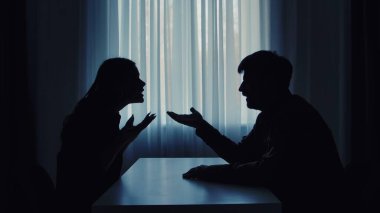 Siluetli bir çift, arka plandaki ışığa karşı hararetli bir tartışmaya girerek çatışma dinamiklerini gösteriyor..
